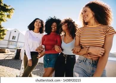 Mixed raced group of female friends walking together outdoors. Young women having fun outdoors at the beach.