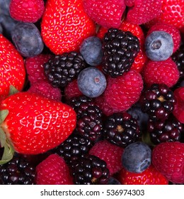 Mixed Ripe Sweet Berries Background. Blueberries Raspberries, Strawberries And Blackberries. Rich Colours. With Space For Text.