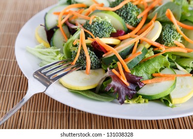 Mixed Salad On White Plate With Mixed Greens, Cucumber, Brocolli, Squash And Carrots