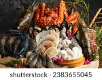 Mixed seafood contain crabs, scallops, mussels, shrimps, squids with lemon on wood bowl.Big set of various fresh sea food on wooden table background.