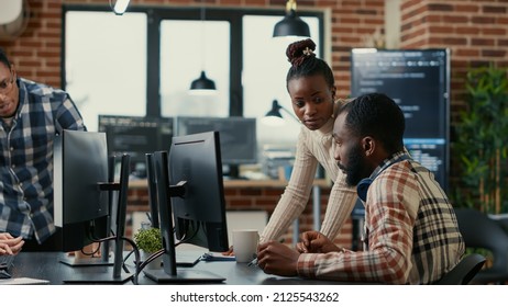 Mixed team of programmers brainstorming ideas for new cloud computing user interface looking at running code on computer screens. Developers collaborating on group project compiling algorithm. - Shutterstock ID 2125543262