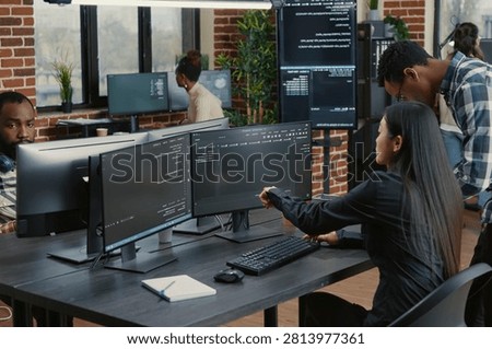 Mixed team of programmers points at screens and compares source code, algorithms and user interface details during a software project review.