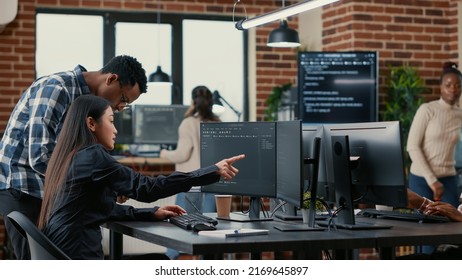 Mixed team of software developers analyzing source code pointing at screens comparing algorithm with user interface on digital tablet. Programmers working on coding group project sitting at desk. - Powered by Shutterstock