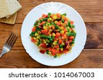 Mixed vegetable stew on a serving plate and wooden table. Homemade stewed carrots, green beans, red beans, peas, corn, pepper and onions. Healthy vegetarian stew. Top view