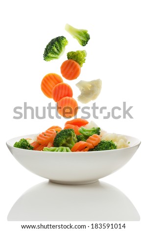 Mixed vegetables falling into a bowl of salad