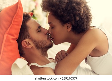 Mixed-race Couple Kissing In Bed.