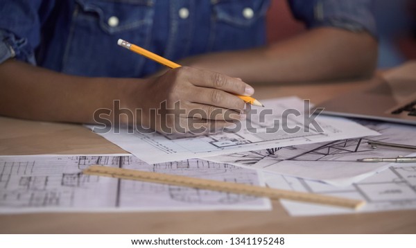 Mixed-race designer working on apartment layout\
plan, holding pencil,\
project