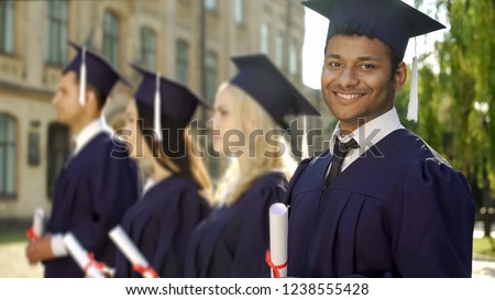 Mixed-race graduate student with diploma smiling into camera, exchange program