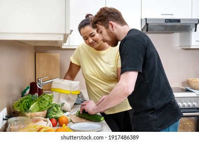 Mixed-race Happy Young Couple Preparing Vegan Food. Attractive Caucasian Man And Mixed-race Woman Preparing Vegan Meal At Kitchen. Vegan Natural Food Cooking. Comfort Cooking. Real Life Concept