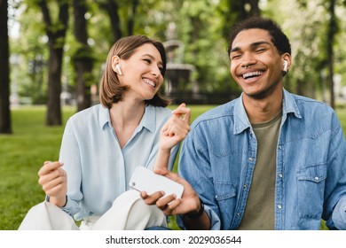 Mixed-race Students Friends Romantic Couple Freelancers Listening To The Podcast Radio Music Favorite Singer Song Playlist In Earbuds Earphones Using Musical Application Walking In City Park Outdoors