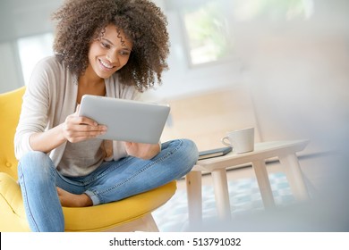 Mixed-race woman websurfing on digital tablet at home - Shutterstock ID 513791032