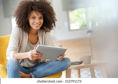 Mixed-race woman websurfing on digital tablet at home - Shutterstock ID 513791173
