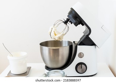 Mixer Bowl Of Whipped Cream. White Kitchen Background. Homemade Culinary Concept. Mixing, Whipping Cream For Cake. Concept Of Confectionery, Cooking Desserts And Kitchenware, Homemade Culinary.