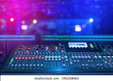 A mixer for mixing music with buttons and screen and a blue and pink background under low light conditions.