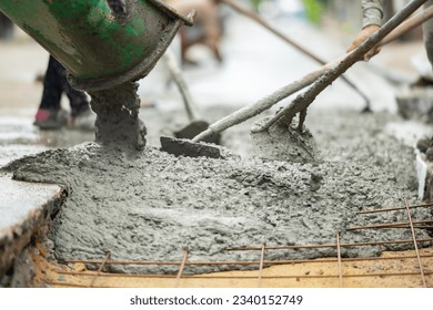 Mixer truck pouring cement concrete casting on reinforcing metal bars of sidewalk. Concrete mixer truck, transport and combine cement and water in revolving drum. Worker using shovel and scoop at work