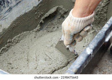 Mixing Concrete By Hand. Scooping Up The Concrete Mixture With A Trowel