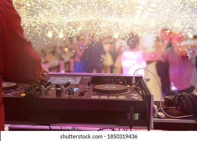 Mixing Console Is Played By DJ And Couples Dancing On The Dance Floor In The Background And Empty Space For Text