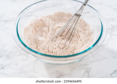 Mixing dry ingredients in a large glass mixing bowl to bake eggnog cookies with a chocolate gingerbread man. - Shutterstock ID 2194656495