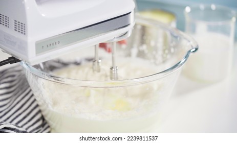 Mixing ingredients in a glass mixing bowl to prepare homemade coconut ice cream.