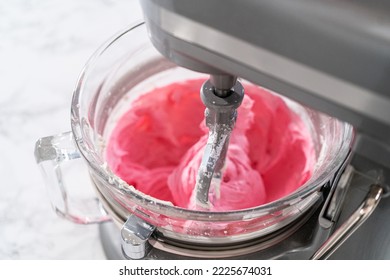 Mixing ingredients in kitchen electric mixer to make ombre pink buttercream frosting. - Shutterstock ID 2225674031
