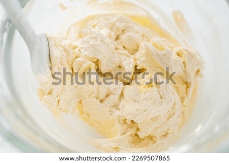 Mixing ingredients in kitchen electric mixer to make lemon buttercream frosting.