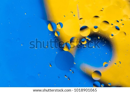 mixing water and oil, beautiful color abstract background based on yellow and blue circles and ovals, blurred macro abstraction