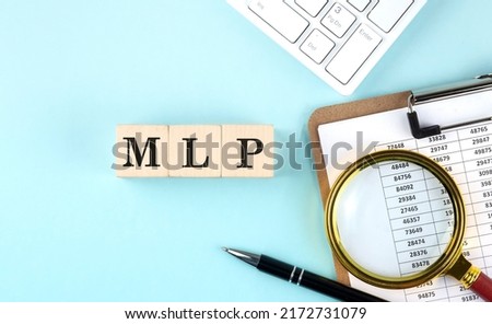 MLP - Master Limited Partnership word on a wooden cubes on a blue background with chart and keyboard