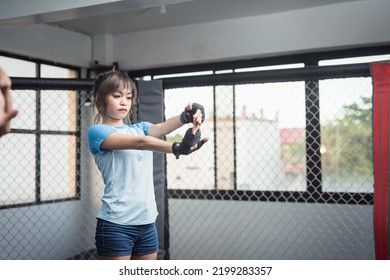 An MMA Female Athlete Does An Extended Arm Wand Wrist Stretch As She In The Ring Cage For Her Vigorous Training.