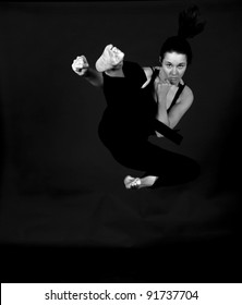 MMA - Female Mixed Martial Arts Warrior Kicking On A Black Background.