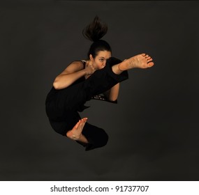 MMA - Female Mixed Martial Arts Warrior Kicking On A Black Background.