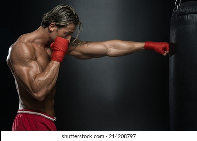 MMA Fighter Practicing With Boxing Bag - A Man With A Tattoo In Red Boxing Gloves - Boxing On Black Background - The Concept Of A Healthy Lifestyle - The Idea For The Film About Boxing - Powered by Shutterstock