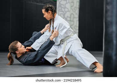 Mma, karate and jiu jitsu with two female athletes practicing, training and sparring in fight class. Healthy, fit and active women in gi or uniform learning self defense for safety and health - Powered by Shutterstock