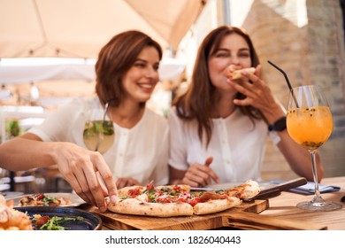 Mmm, so delicious! Delighted best friends sitting at the cafe and enjoying pizza - Powered by Shutterstock