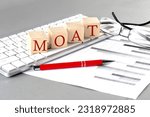 MOAT written on wooden cube on the keyboard with chart on grey background