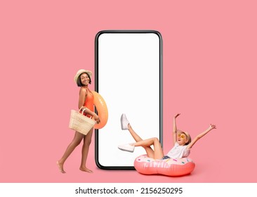 Mobile Ad. Two Cheerful Multiethnic Women In Summer Outfits Having Fun Near Big Blank Smartphone, Black Lady Holding Swimming Circle While Her Joyful Female Friend Sitting In Inflatable Donut, Mockup