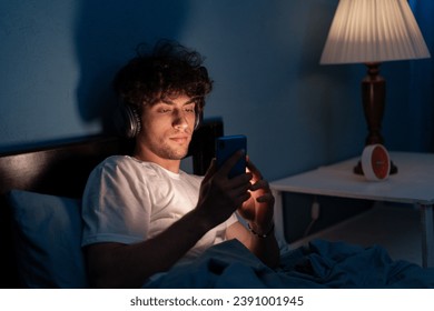 mobile addict man using smartphone browsing the internet for watching movie or have video call online on the bed no sleeping at night. Copy space - Powered by Shutterstock