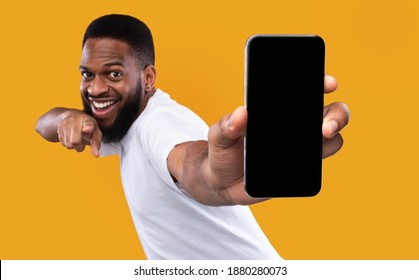 Mobile App Advertisement. Excited Black Man Showing Smartphone Empty Screen Recommending App Posing Over Yellow Studio Background, Smiling To Camera. Check This Out, Cellphone Display Mockup - Shutterstock ID 1880280073
