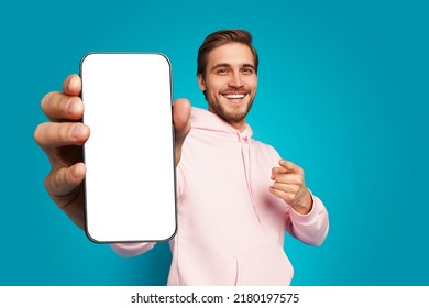 Mobile App Advertisement. Handsome Excited Man Showing Pointing At Empty Smartphone Screen Posing Over Light Blue Studio Background, Smiling To Camera. Check This Out, Cellphone Display Mock Up - Shutterstock ID 2180197575