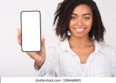 Mobile App Advertising. African woman showing blank cellphone screen, mockup, selective focus