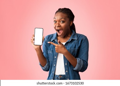 Mobile App. Excited African American Lady Showing Phone Pointing Finger At Blank Screen Posing Over Pink Studio Background. Mockup