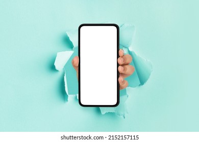 Mobile App, Great Offer. Male hand holding smartphone with white empty screen showing device close up to camera breaking through blue paper sheet. Gadget display with free copy space, mock up banner