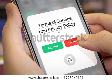 Mobile app user refusal to accept Terms of Service and the Privacy Policy. Finger presses the Decline button in app interface. Light theme, close-up