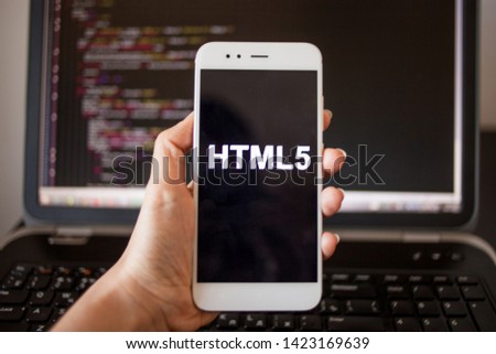 Mobile application development, HTML5 programming language for mobile development. Smartphone in hand with the inscription HTML5 on the screen