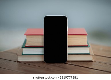 Mobile Application. Smartphone With Empty Black Screen Standing Near Stack Of Books On Table Outdoors. Mockup For Educational App Advertisement With Phone Gadget. Technology, E-Learning