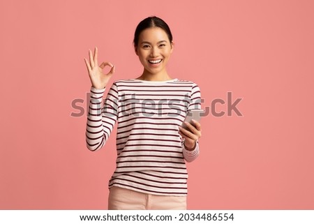 Mobile Banking. Happy Young Asian Woman Holding Smartphone And Showing Ok Gesture, Cheerful Korean Female Enjoying Making Payments Online While Standing Isolated Over Pink Background, Copy Space
