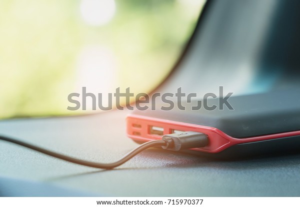 Mobile Battery with USB cable on dashboard car\
horizontal background