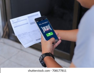 Mobile bill payment barcode scan concept.Man hands using mobile phone and holding bills