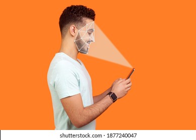 Mobile biometric identification and verification or detection concept. face ID scaning or unlocking technology. happy man using facial recognition on smartphone. indoor isolated on orange background.