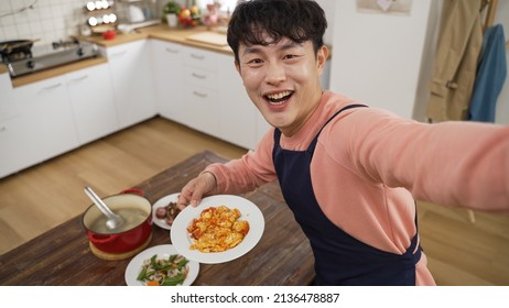 Mobile Cam View Of Happy Asian Dad Showing Delicious Dish He Made To Family Through Video Chat Online Call. He Looks At Camera While Smelling Food And Boasting About His Cooking