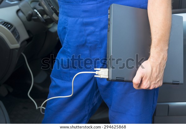 Mobile car service engineer checking car with his\
laptop on the road